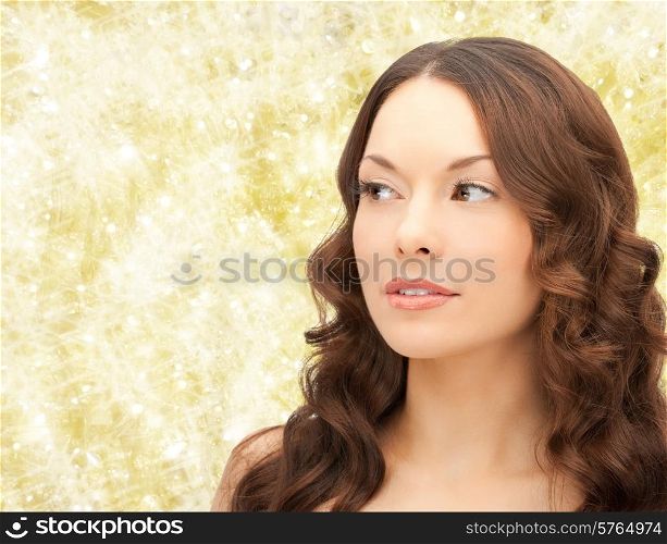 beauty, people and health concept - beautiful young woman face over yellow lights background