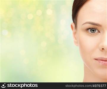 beauty, people and health concept - beautiful young woman half face over green lights background. beautiful young woman half face over green