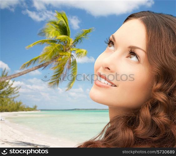 beauty, people and health concept - beautiful young woman looking up over blue lights background