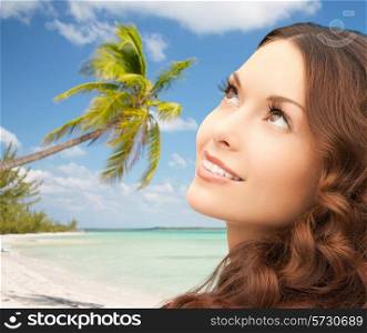 beauty, people and health concept - beautiful young woman looking up over blue lights background