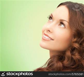 beauty, people and health concept - beautiful young woman looking up over green background