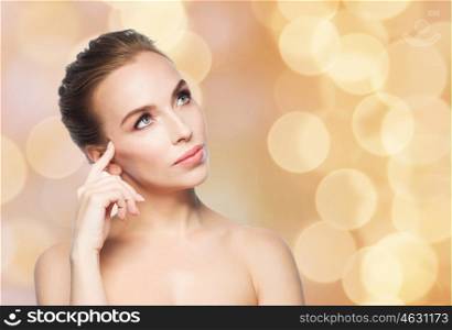 beauty, people and health concept - beautiful young woman looking up over holidays lights background