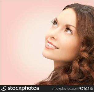 beauty, people and health concept - beautiful young woman looking up over pink background