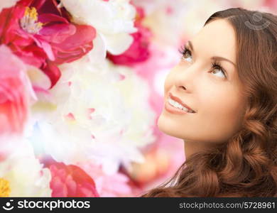 beauty, people and health concept - beautiful young woman looking up over pink floral background