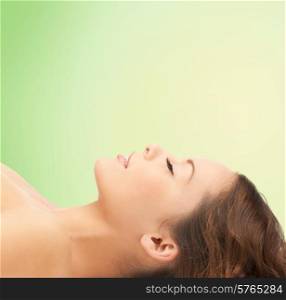 beauty, people and health concept - beautiful young woman lying with closed eyes over green background