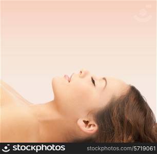 beauty, people and health concept - beautiful young woman lying with closed eyes over pink background