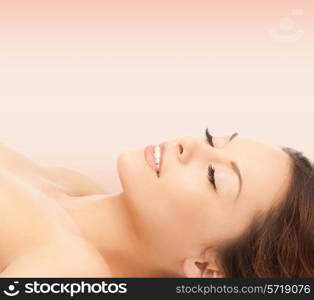 beauty, people and health concept - beautiful young woman lying with closed eyes over pink background