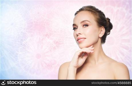 beauty, people and health concept - beautiful young woman touching her face over rose quartz and serenity pattern background