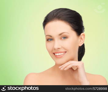 beauty, people and health concept - beautiful young woman touching her face over green background