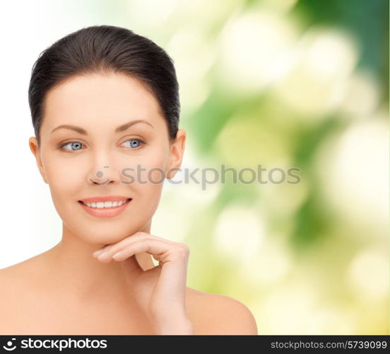 beauty, people and health concept - beautiful young woman touching her face over green background