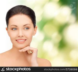 beauty, people and health concept - beautiful young woman touching her face over green background