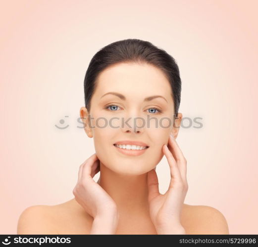 beauty, people and health concept - beautiful young woman touching her face over pink background