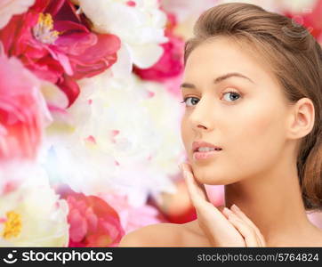 beauty, people and health concept - beautiful young woman touching her face over pink floral background