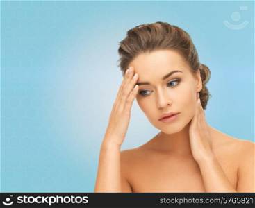 beauty, people and health concept - beautiful young woman touching her head and neck over blue background