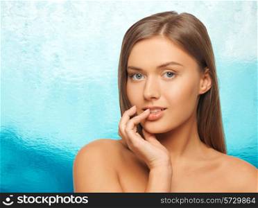 beauty, people and health concept - beautiful young woman touching her lips over ripple blue water background