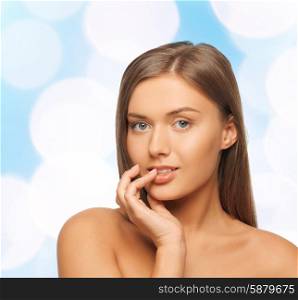 beauty, people and health concept - beautiful young woman touching her lips over blue lights background