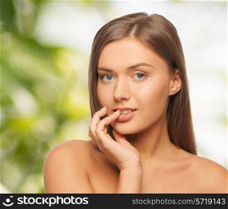 beauty, people and health concept - beautiful young woman touching her lips over green background