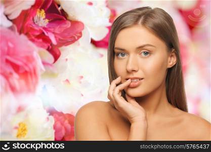 beauty, people and health concept - beautiful young woman touching her lips over pink floral background