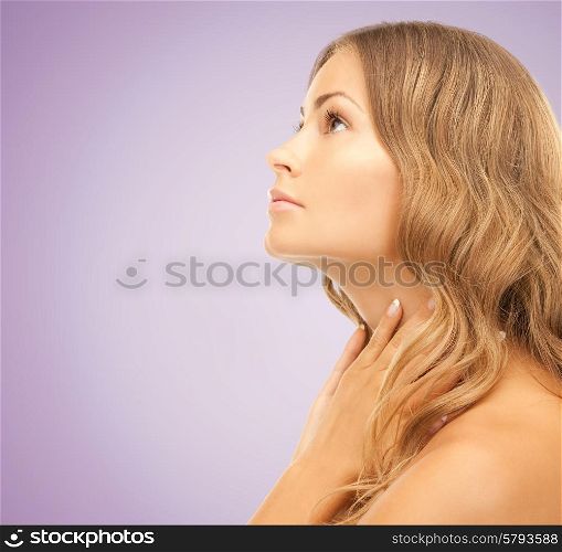 beauty, people and health concept - beautiful young woman touching her neck and looking up over violet background