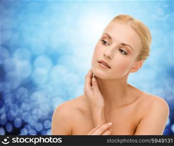 beauty, people and health concept - beautiful young woman touching her neck over blue lights background