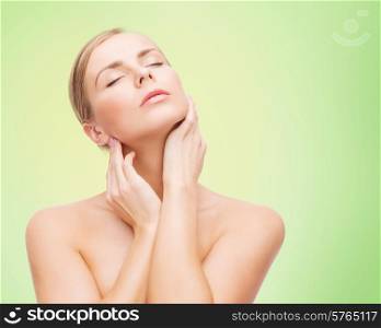 beauty, people and health concept -beautiful young woman touching her neck over green background