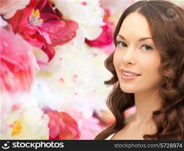 beauty, people and health concept - beautiful young woman with bare shoulders and long wavy hair over pink floral background