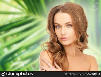 beauty, people and health concept - beautiful young woman with bare shoulders over green palm leaves background
