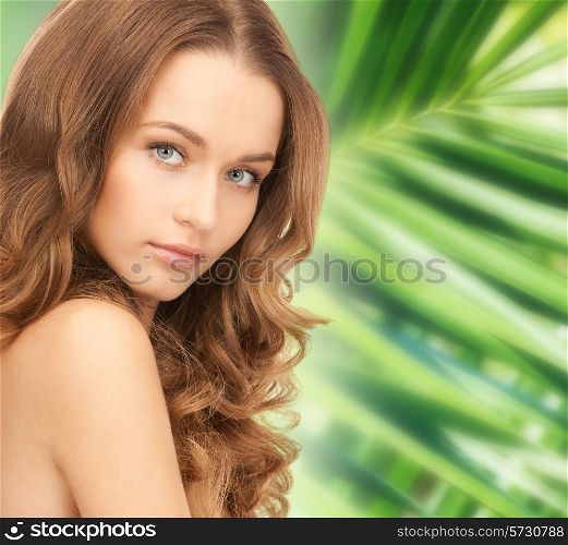 beauty, people and health concept - beautiful young woman with bare shoulders over green palm leaves background