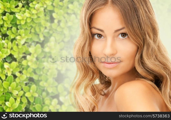 beauty, people and health concept - beautiful young woman with bare shoulders and long wavy hair over green background