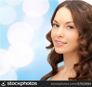 beauty, people and health concept - beautiful young woman with bare shoulders and long wavy hair over blue lights background