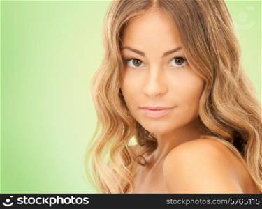 beauty, people and health concept - beautiful young woman with bare shoulders and long wavy hair over green background