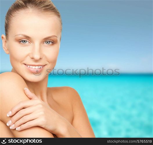beauty, people and health concept - beautiful young woman with bare shoulders over blue water and sky background