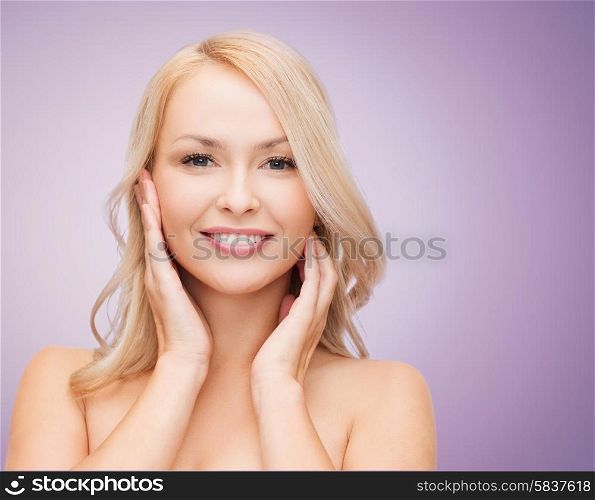 beauty, people and health concept - beautiful young woman with bare shoulders touching her face over violet background