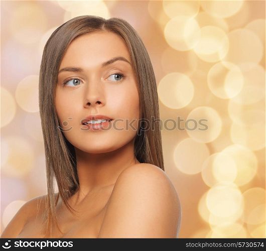 beauty, people and health concept - beautiful young woman with bare shoulders over beige lights background