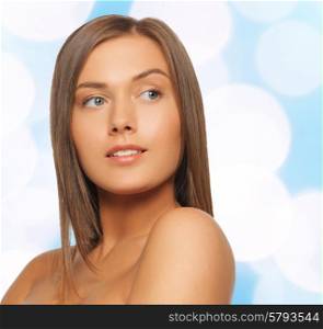 beauty, people and health concept - beautiful young woman with bare shoulders over blue lights background
