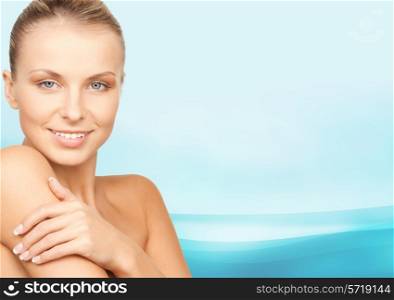 beauty, people and health concept - beautiful young woman with bare shoulders over blue waves background