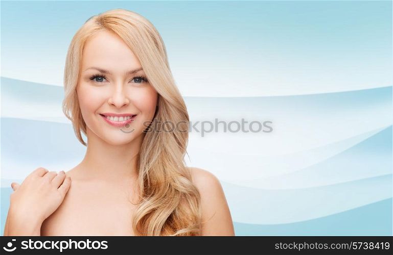 beauty, people and health concept - beautiful young woman with bare shoulders over blue waves background