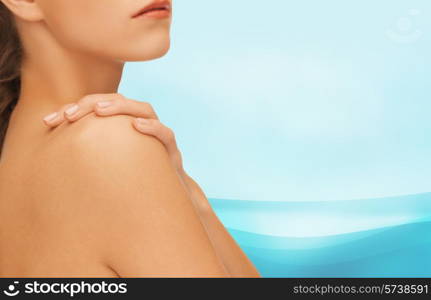 beauty, people and health concept - beautiful young woman with bare shoulders over blue waves background