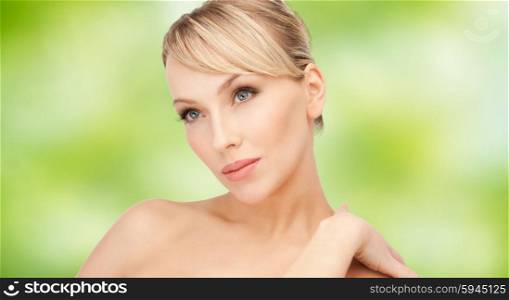 beauty, people and health concept - beautiful young woman with bare shoulders over green natural background