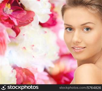 beauty, people and health concept - beautiful young woman with bare shoulders over pink floral background