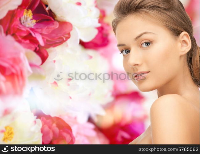 beauty, people and health concept - beautiful young woman with bare shoulders over pink floral background