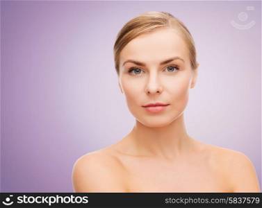 beauty, people and health concept - beautiful young woman with bare shoulders over violet background