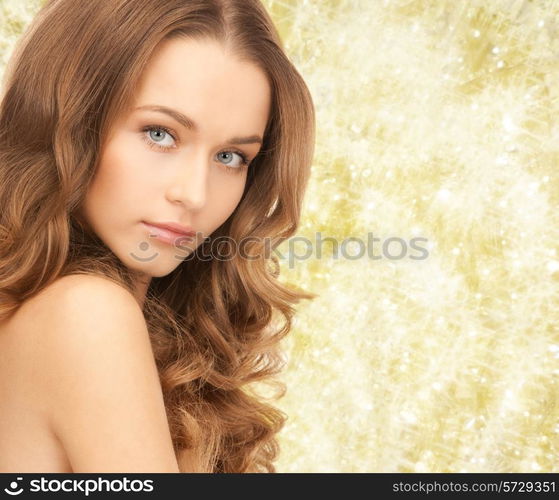 beauty, people and health concept - beautiful young woman with bare shoulders over yellow lights background