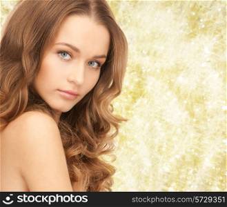 beauty, people and health concept - beautiful young woman with bare shoulders over yellow lights background
