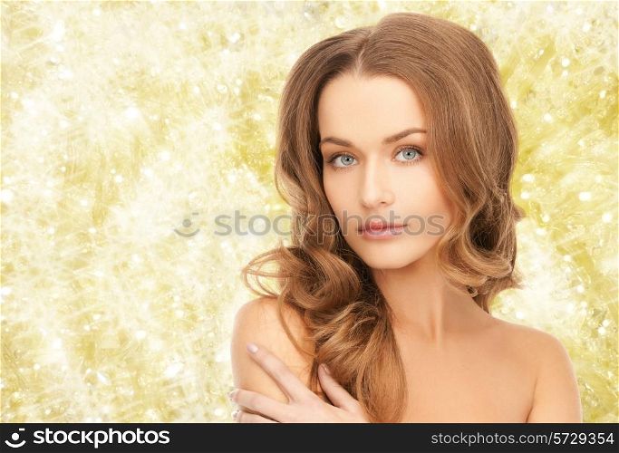 beauty, people and health concept - beautiful young woman with bare shoulders over yellow lights background