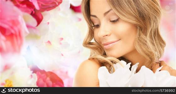beauty, people and health concept - beautiful young woman with flowers and bare shoulders over pink floral background