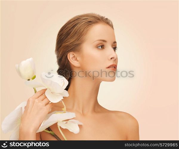 beauty, people and health concept - beautiful young woman with orchid flowers and bare shoulders over pink background