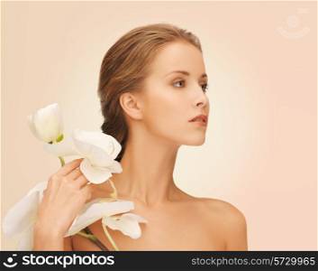 beauty, people and health concept - beautiful young woman with orchid flowers and bare shoulders over pink background
