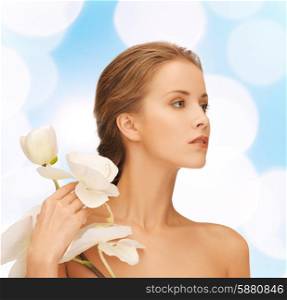 beauty, people and health concept - beautiful young woman with orchid flowers and bare shoulders over blue lights background