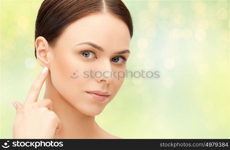 beauty, people and health concept - close up of beautiful young woman face over green lights background. close up of beautiful young woman face over green